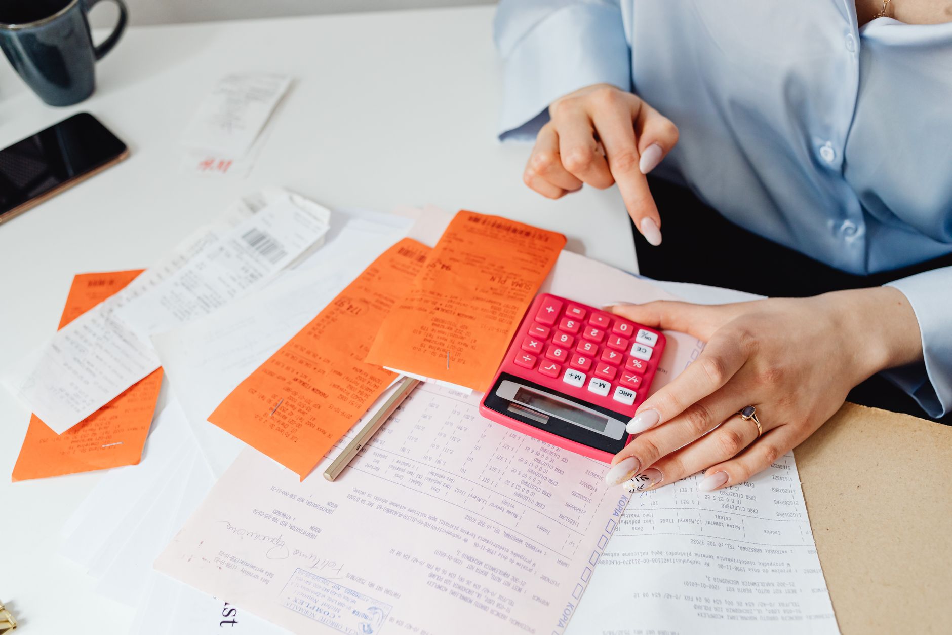 Autónoma calculando sus ingresos y cotizaciones con calculadora y recibos sobre la mesa